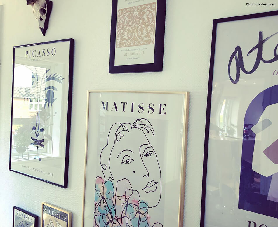 Parete di quadri con cornici nere e dorate