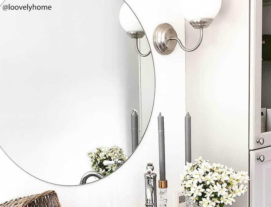 Specchio rotondo, fiori e candele in bagno
